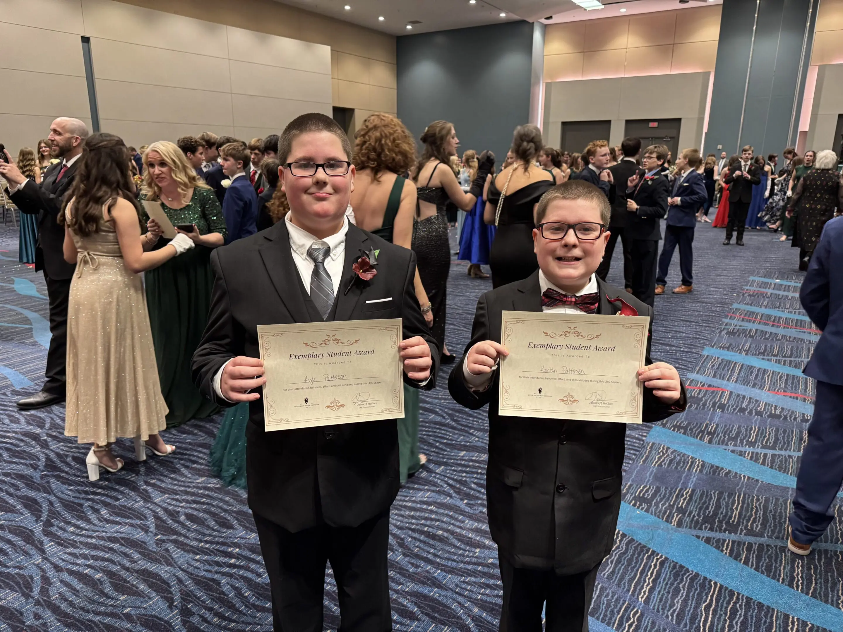 Two formally dressed LRJC students holding student achievement certificates